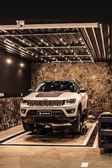 Jeep Compass branco no box do estúdio, com parede de pedra ao fundo