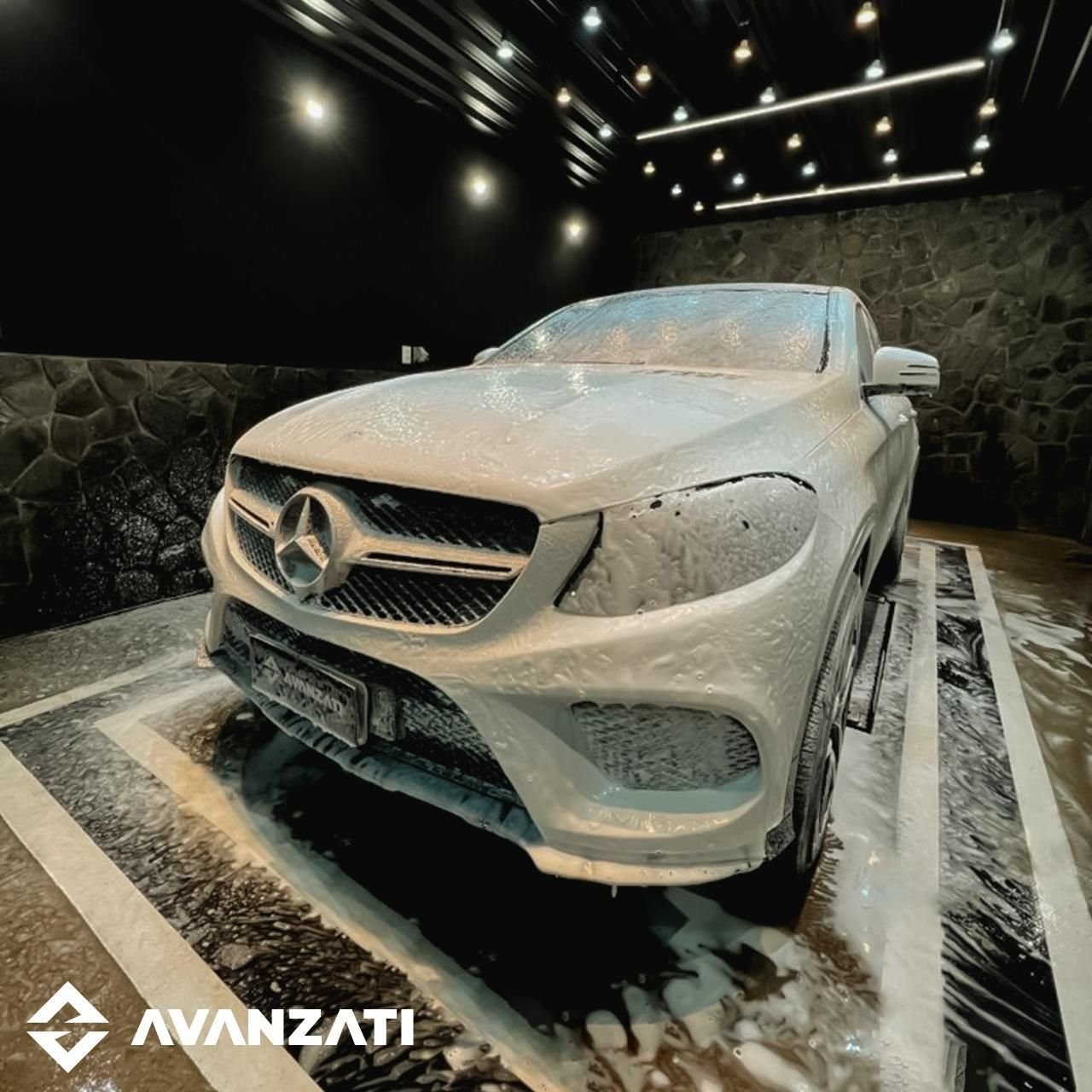 Mercedes GLE coberto de espuma da pré-lavagem no box com parede de pedra